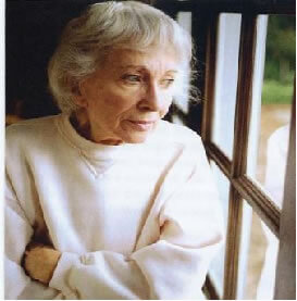 Mujer mayor mirando por la ventana ligeramente entristecida